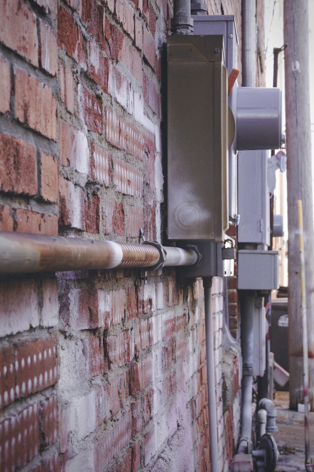 brown metal pipe on red brick wall