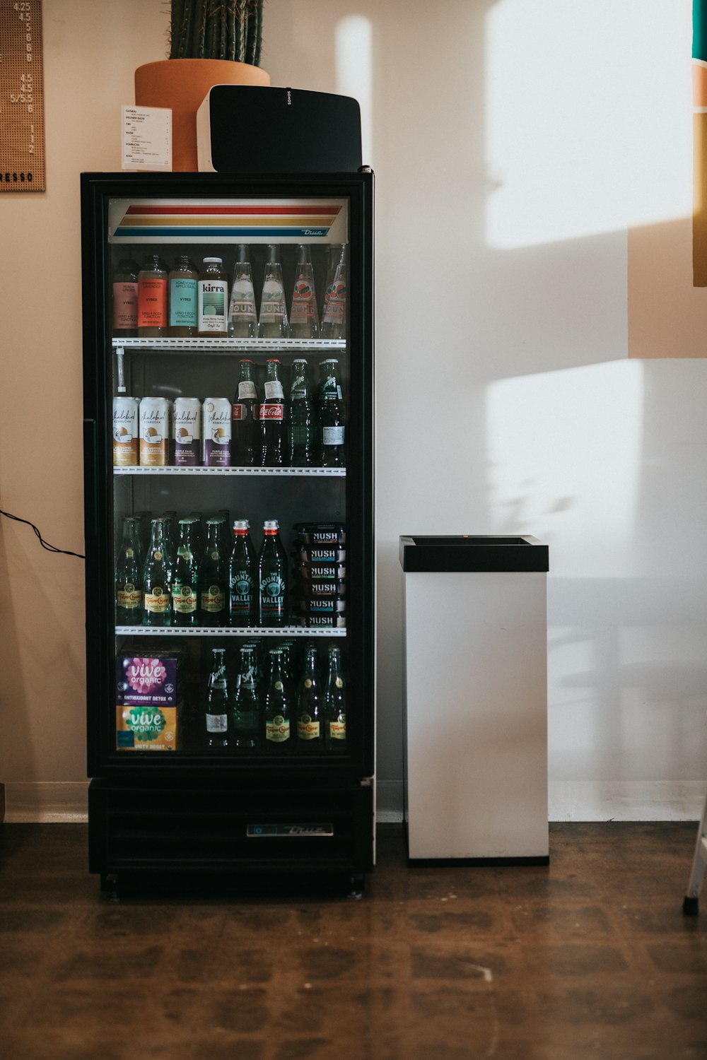 a beverage cooler sitting next to a refrigerator filled with drinks