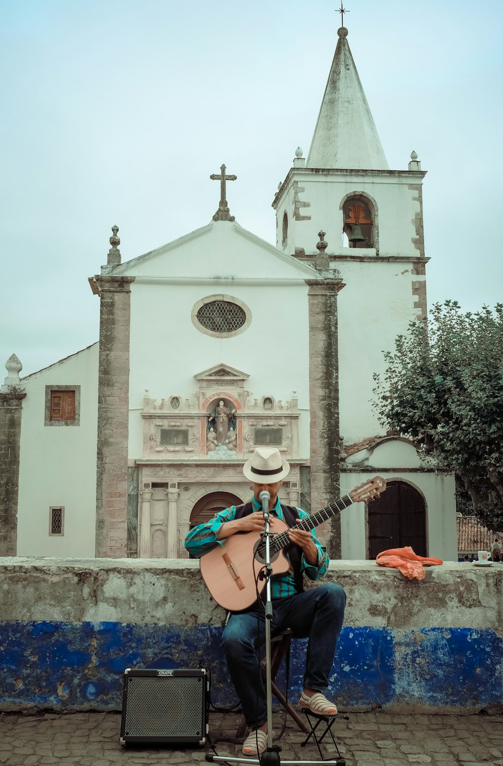 homme en jean bleu jouant de la guitare acoustique marron