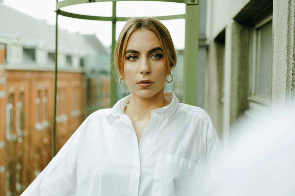woman in white button up shirt standing near glass window