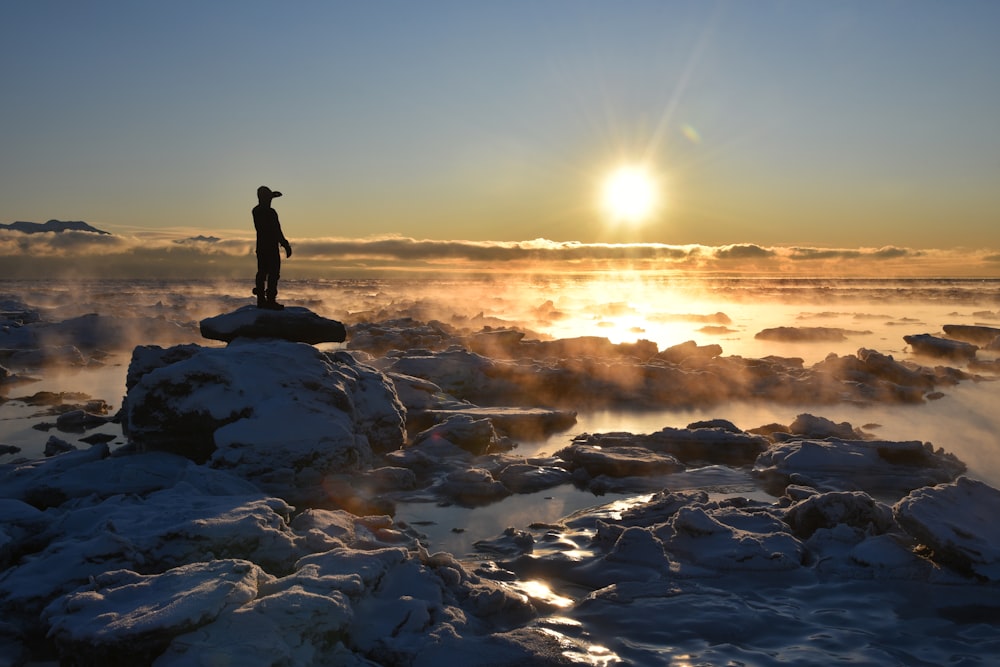 man standing on rock formation near sea during daytime