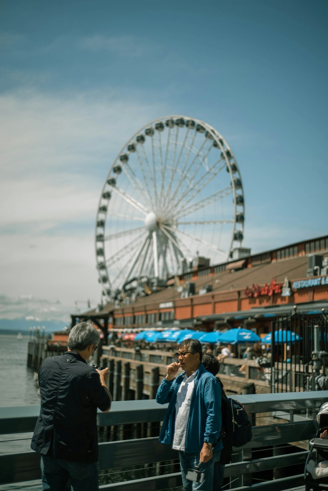 people walking on bridge near ferris wheel during daytime