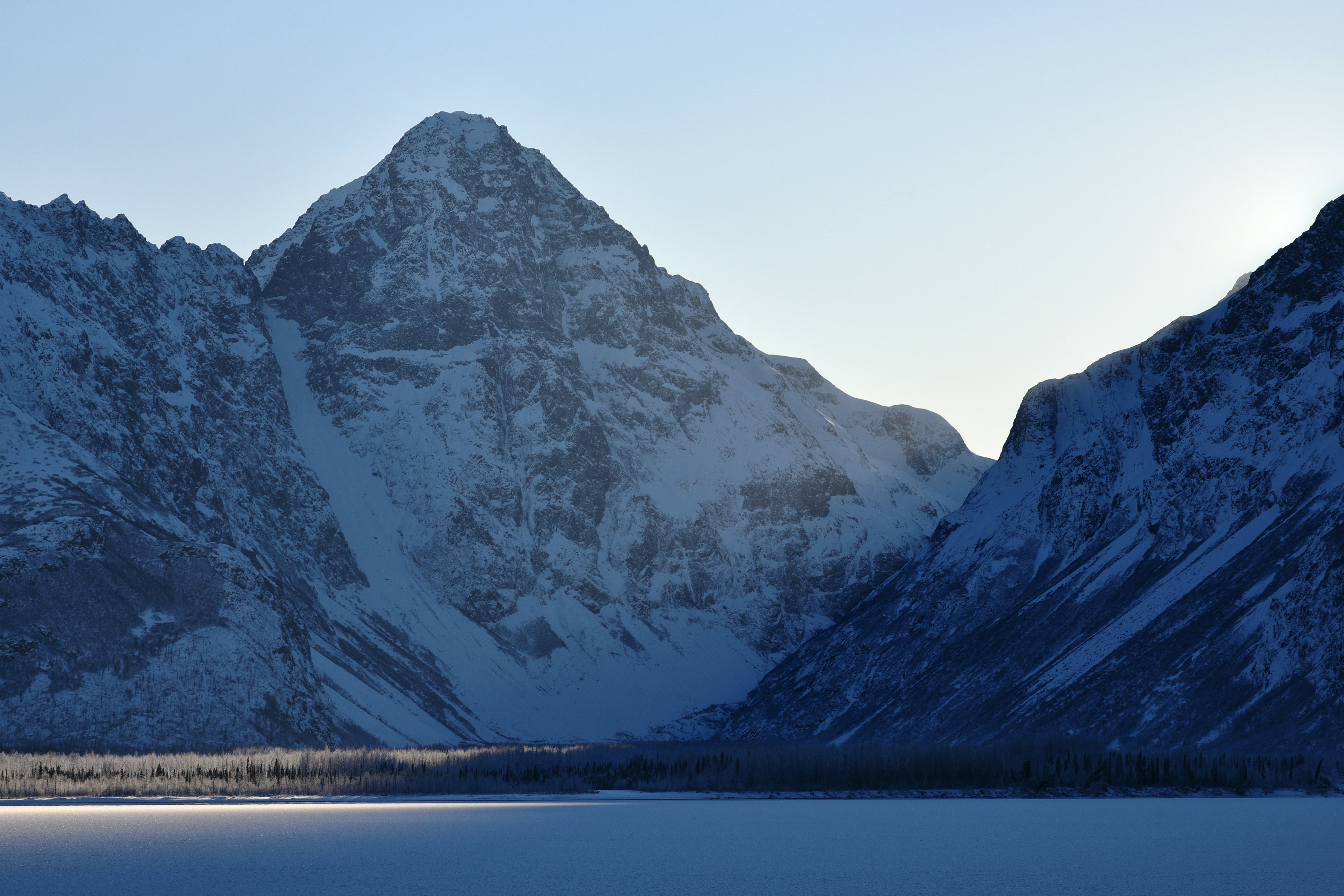snow covered mountain near body of water during daytime
