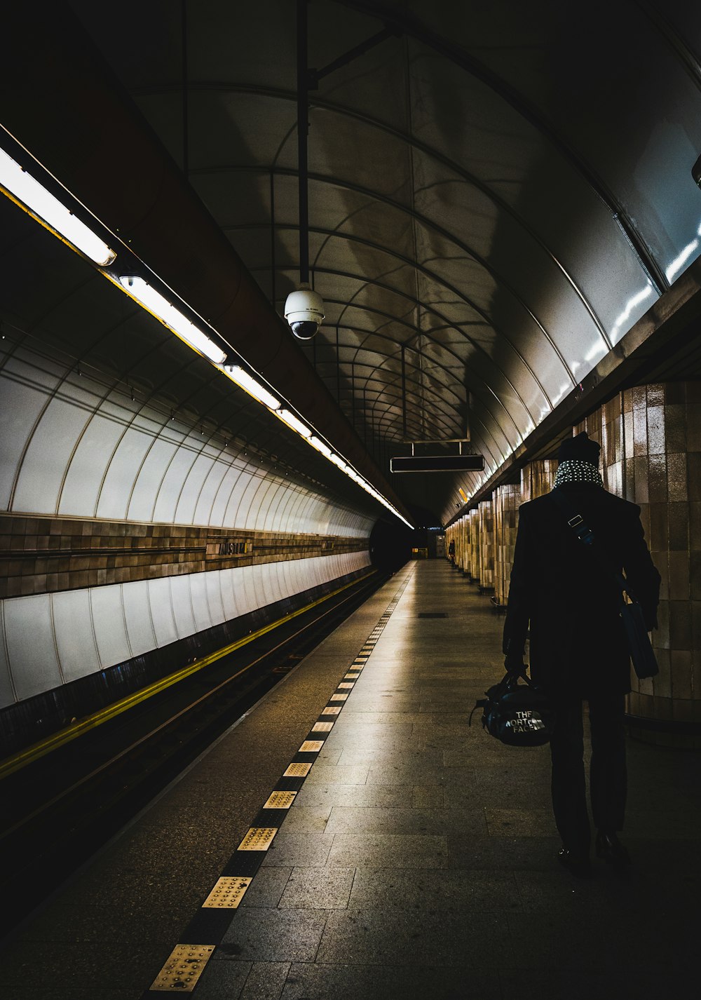 man in black jacket walking on train station