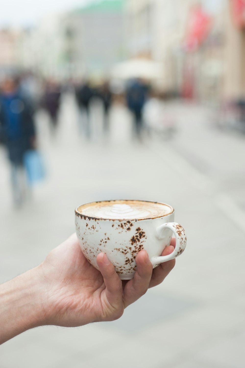 personne tenant une tasse à thé en céramique florale blanche et brune