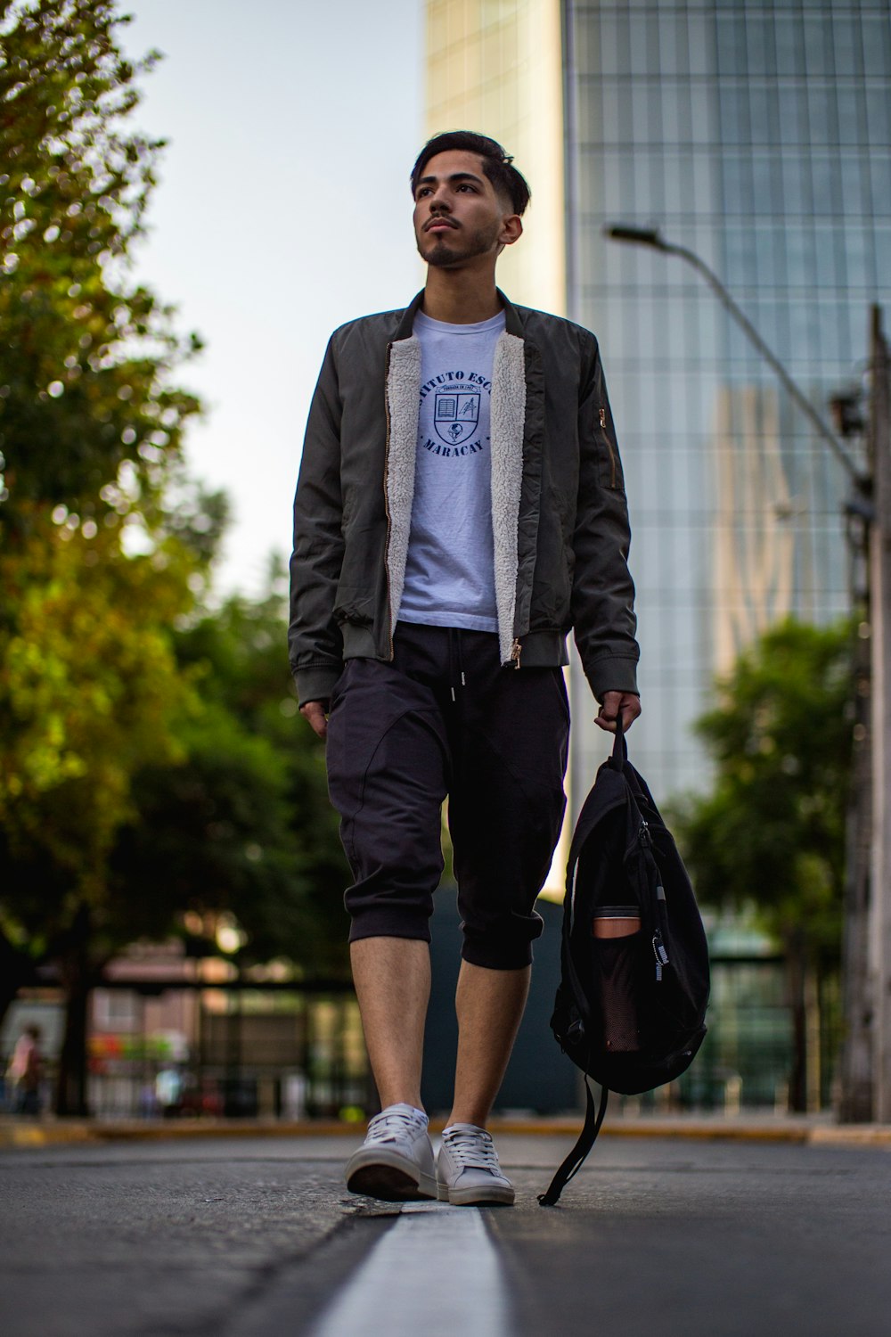 man in gray blazer and black shorts holding black plastic bag