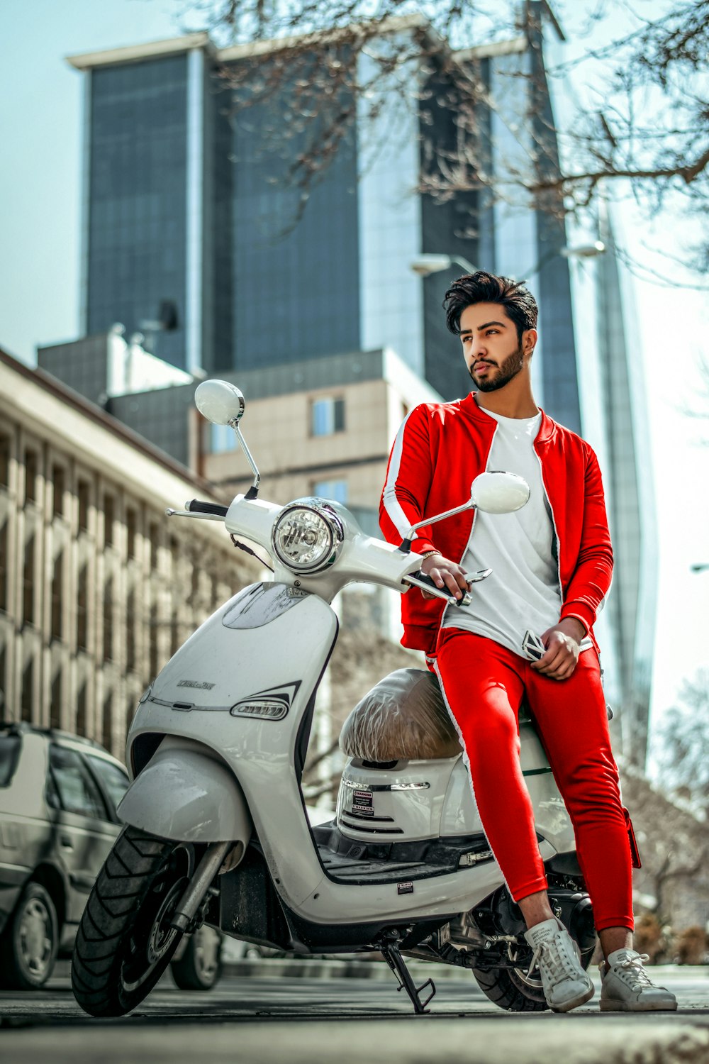 woman in red pants riding white motor scooter during daytime