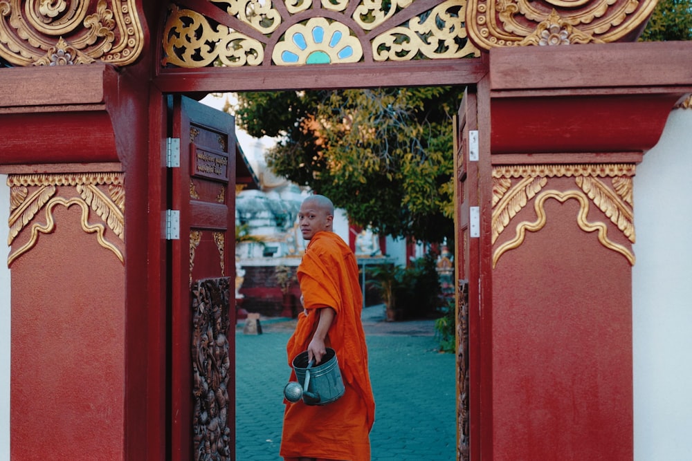 woman in orange hijab standing in front of red wooden door