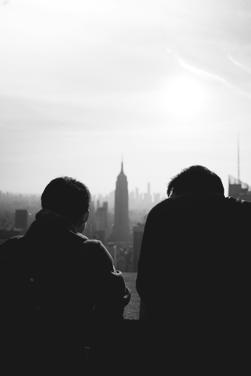 silhouette of 2 person standing near high rise building during daytime