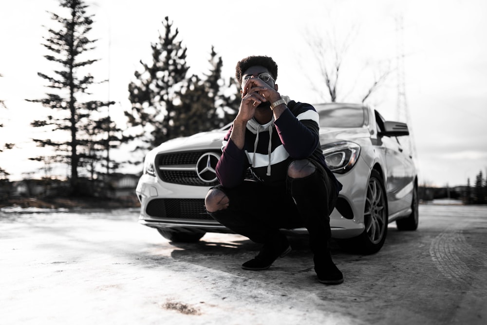 man in black jacket and black pants sitting on black car