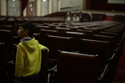 a young boy standing in a row of empty chairs
