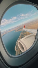 white and red airplane wing over the sea during daytime