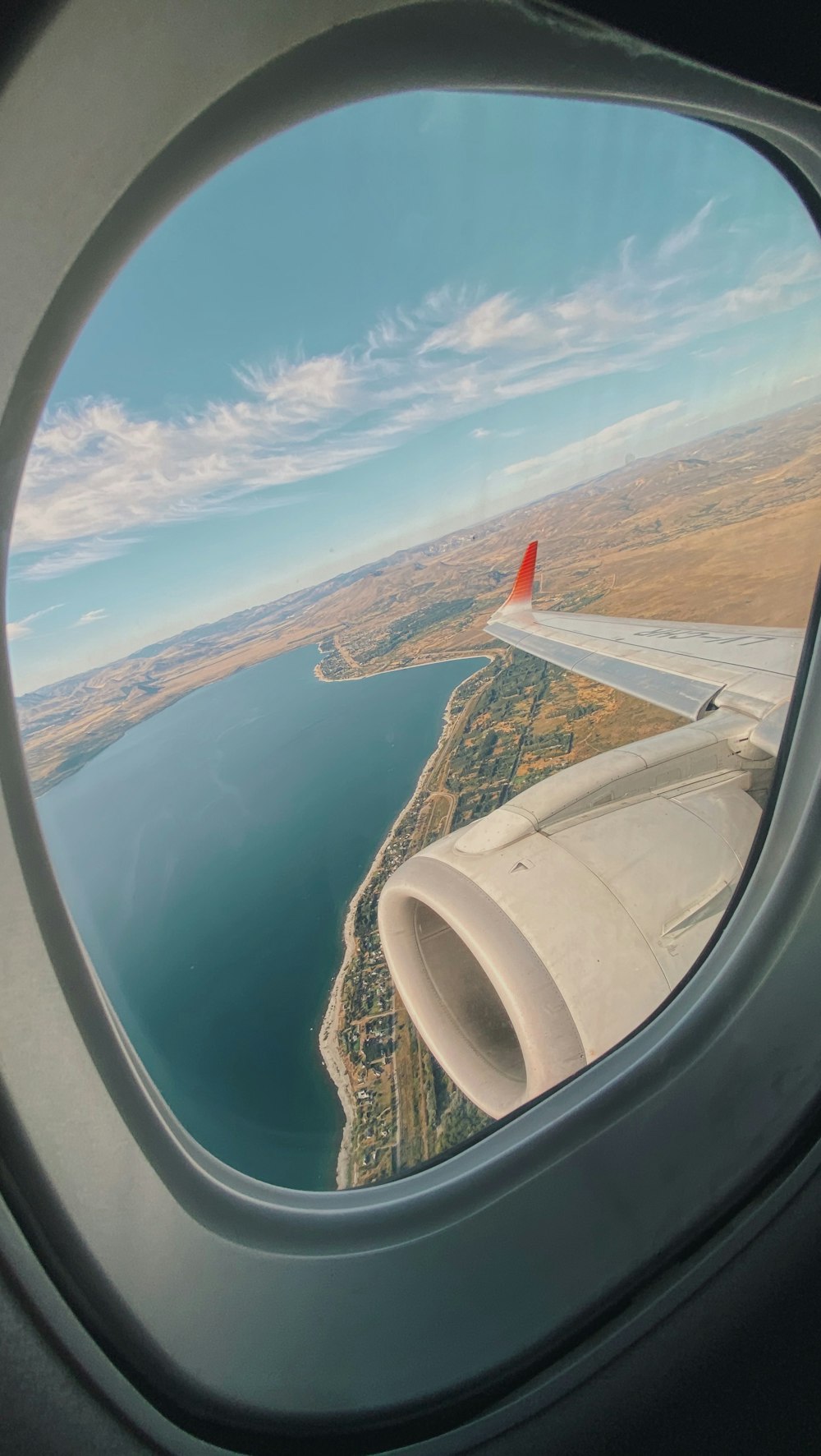 asa do avião branca e vermelha sobre o mar durante o dia