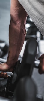 person in gray shirt holding black dumbbell