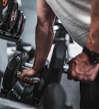 person in gray shirt holding black dumbbell