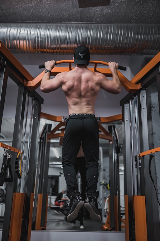 topless man in black pants and black nike shoes