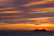 Smiling woman on a cruise ship deck with ocean and sunset in the background.