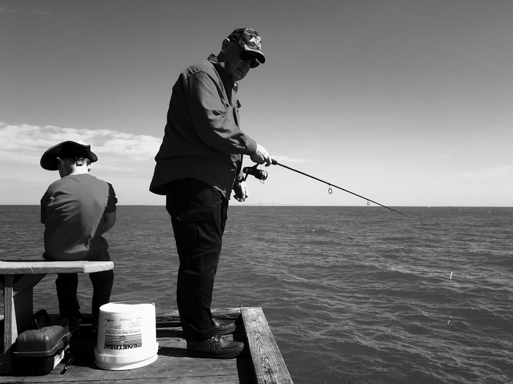 man in black jacket and pants fishing on sea