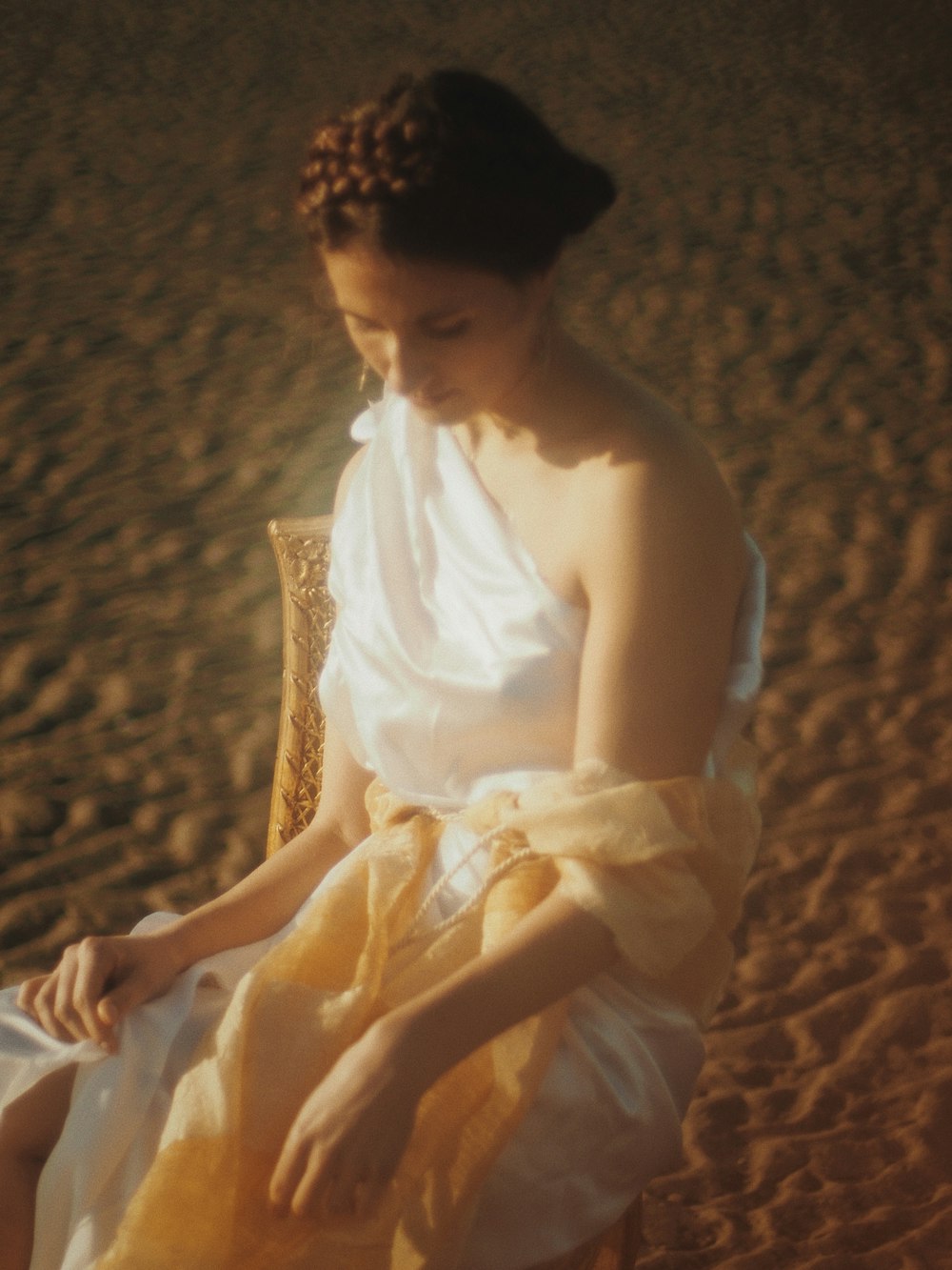 woman in white sleeveless dress sitting on brown textile