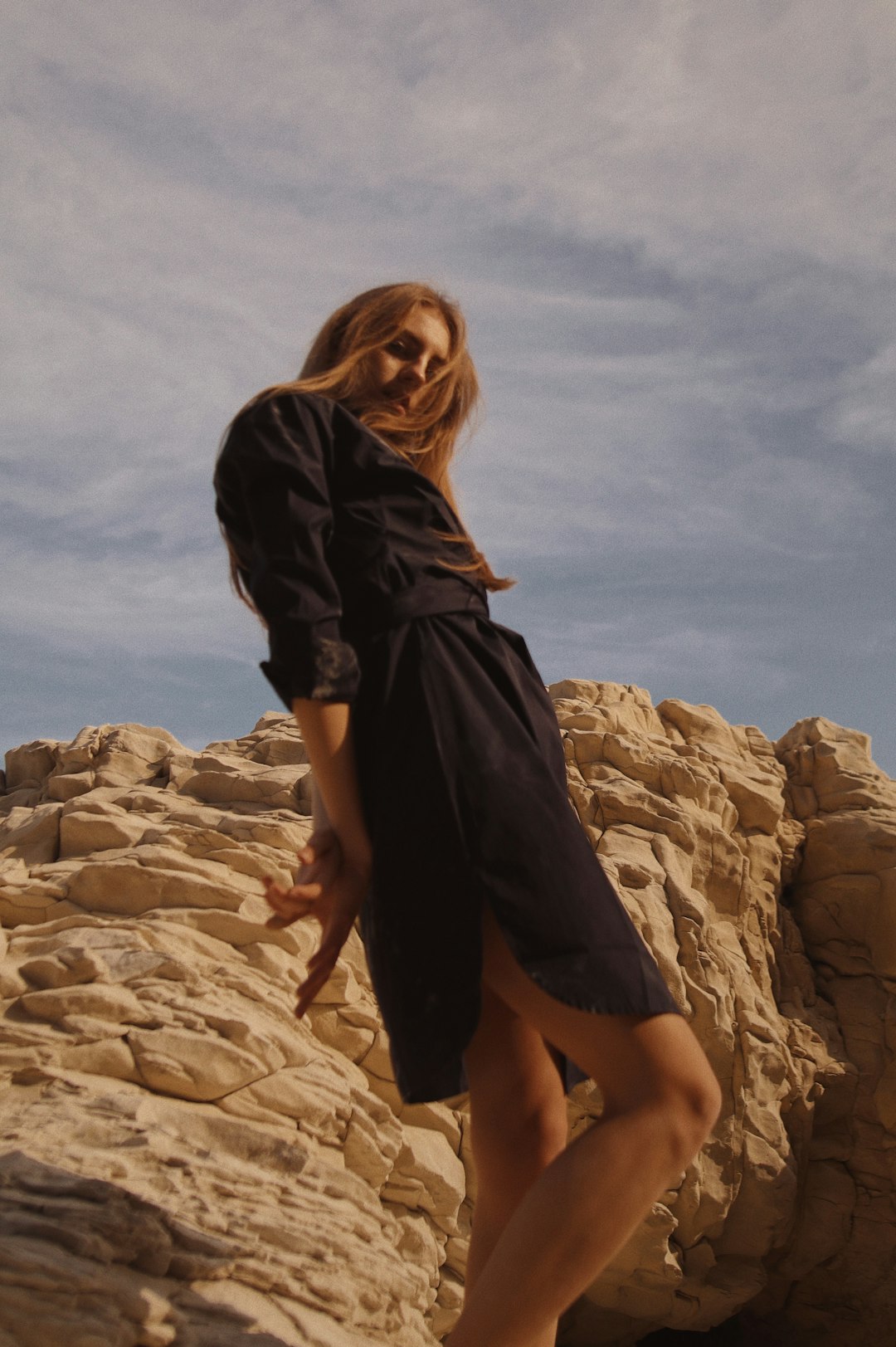 woman in black dress standing on brown rock formation during daytime