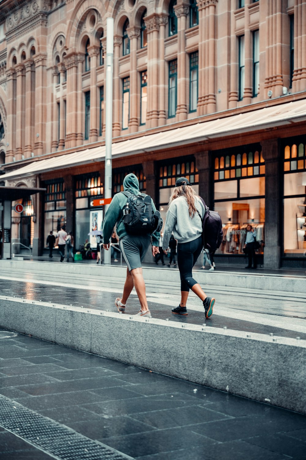 woman in green jacket walking on sidewalk during daytime