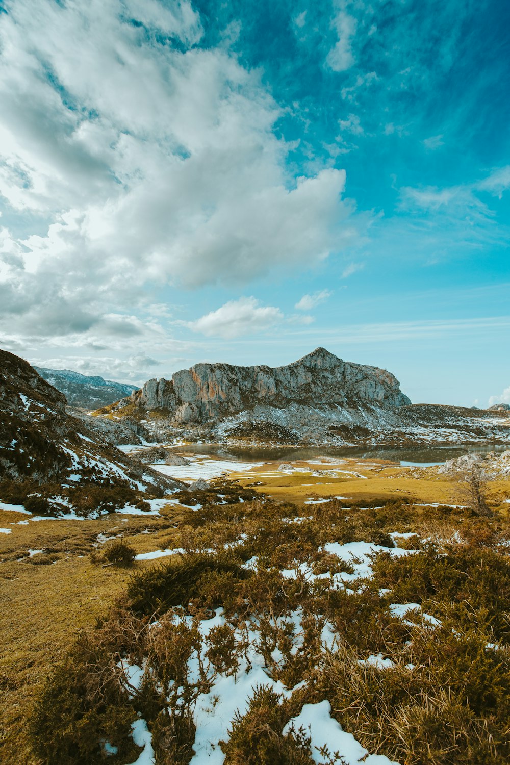 campo de hierba verde cerca de la montaña bajo el cielo azul durante el día