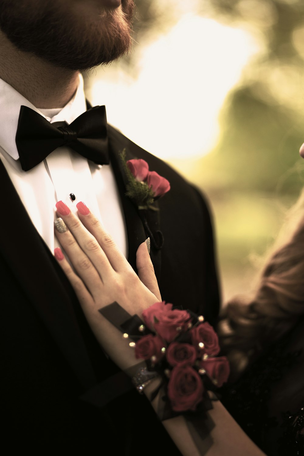 man in black suit jacket holding red rose bouquet