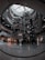 A large, multi-level shopping mall with a modern architectural design. The central area features a tall glass ceiling that allows natural light to illuminate the space. There are multiple floors visible with escalators and various storefronts that include popular fashion brands.