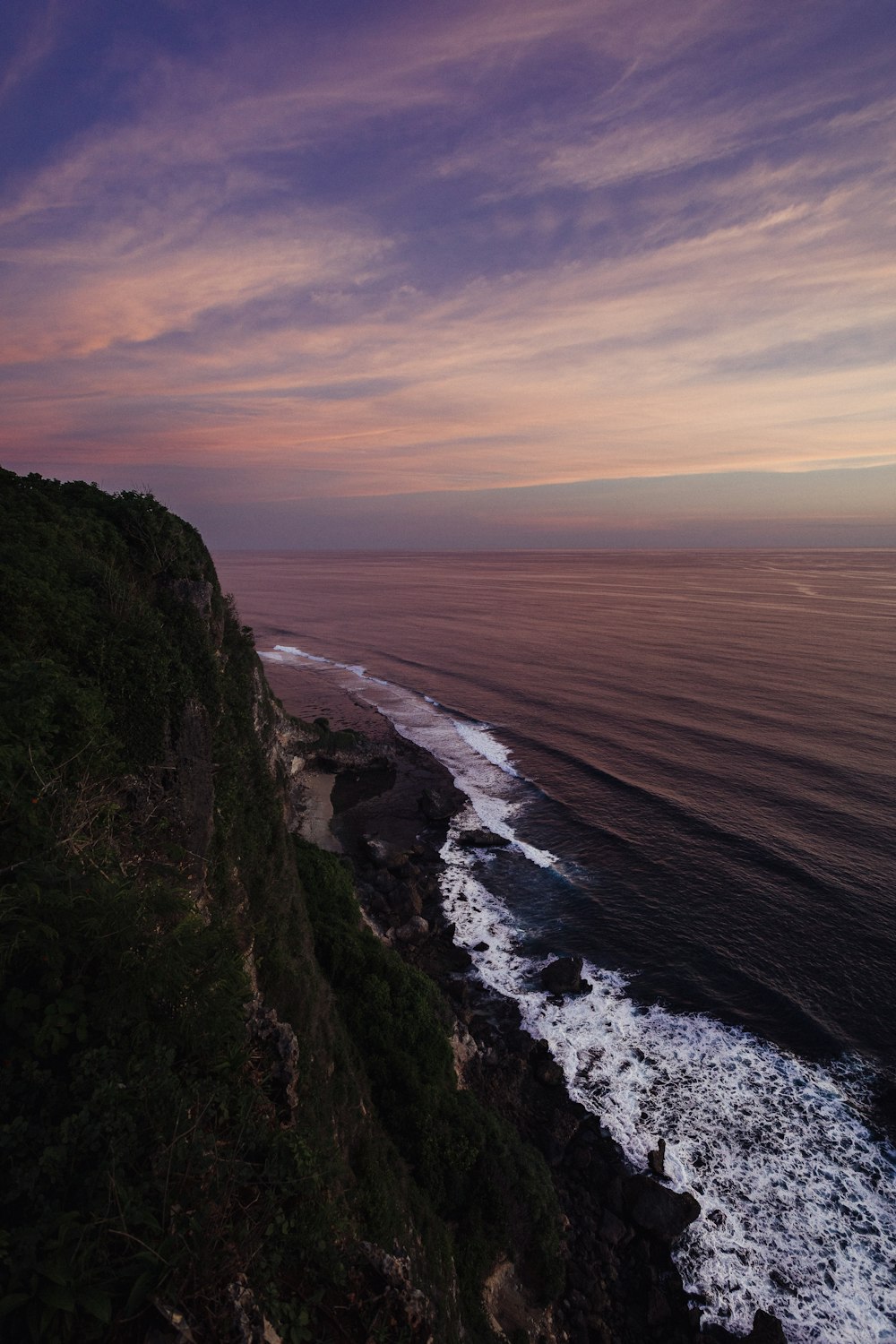 green and brown mountain beside sea during sunset