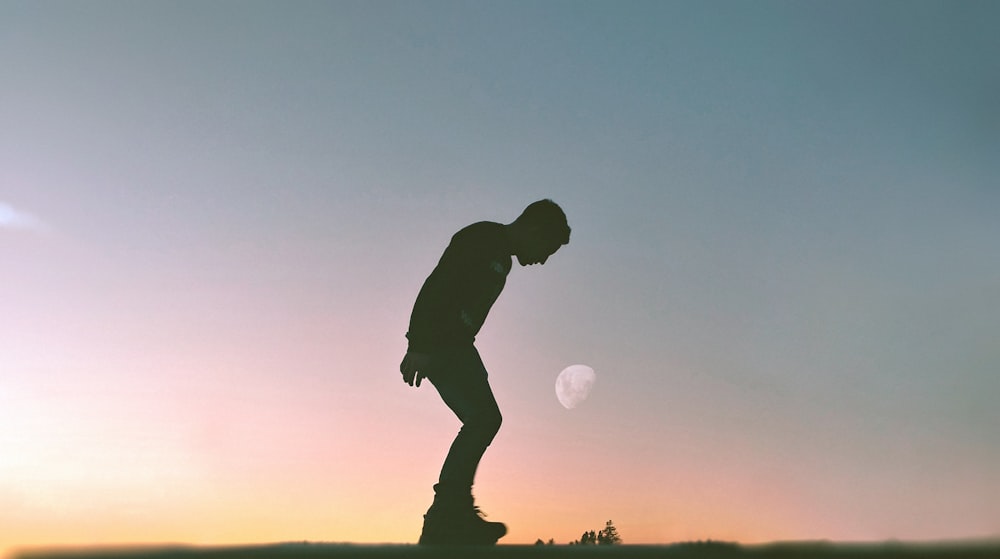 silhouette of man playing with ball during sunset
