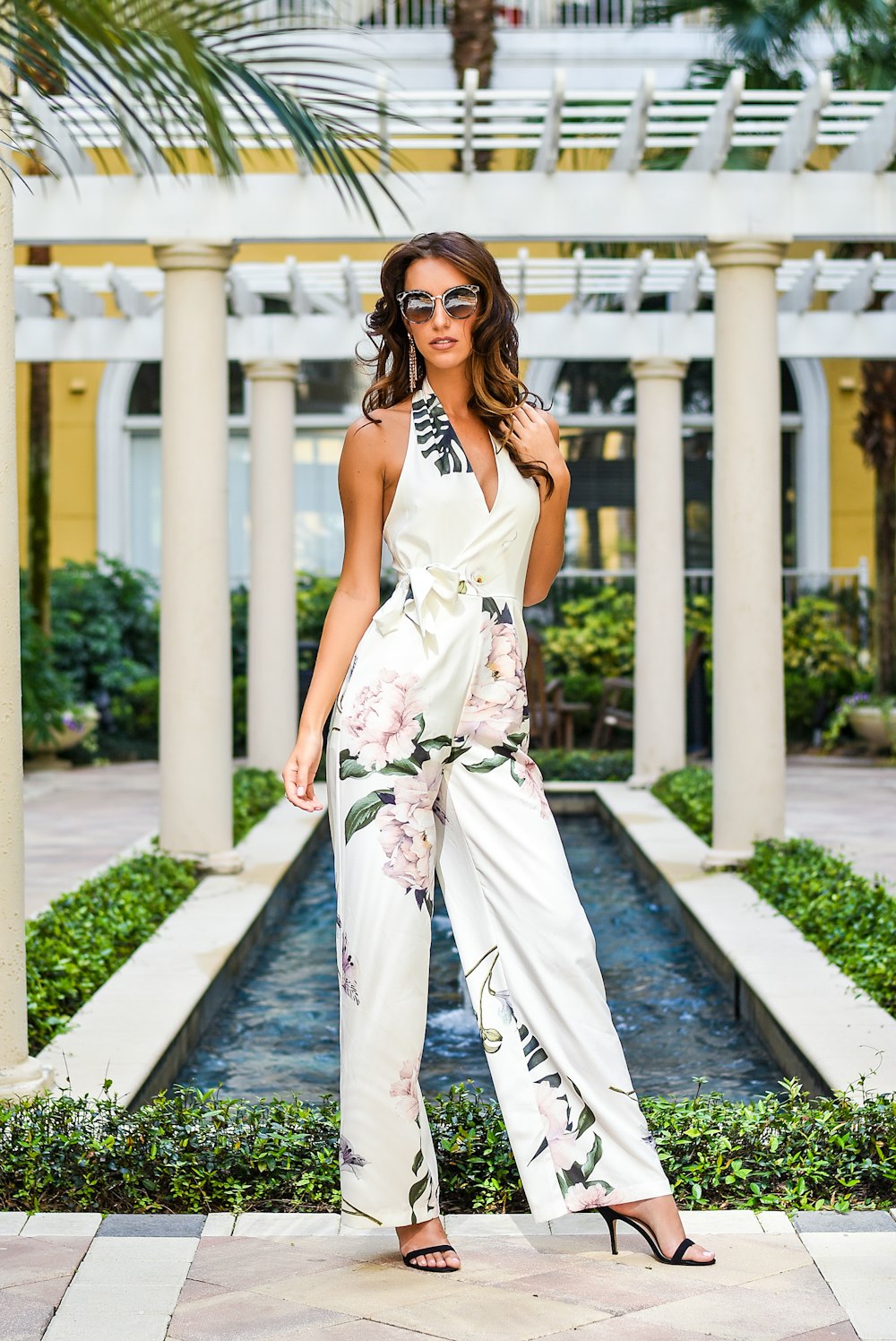 woman in white floral sleeveless dress standing on gray concrete pathway during daytime