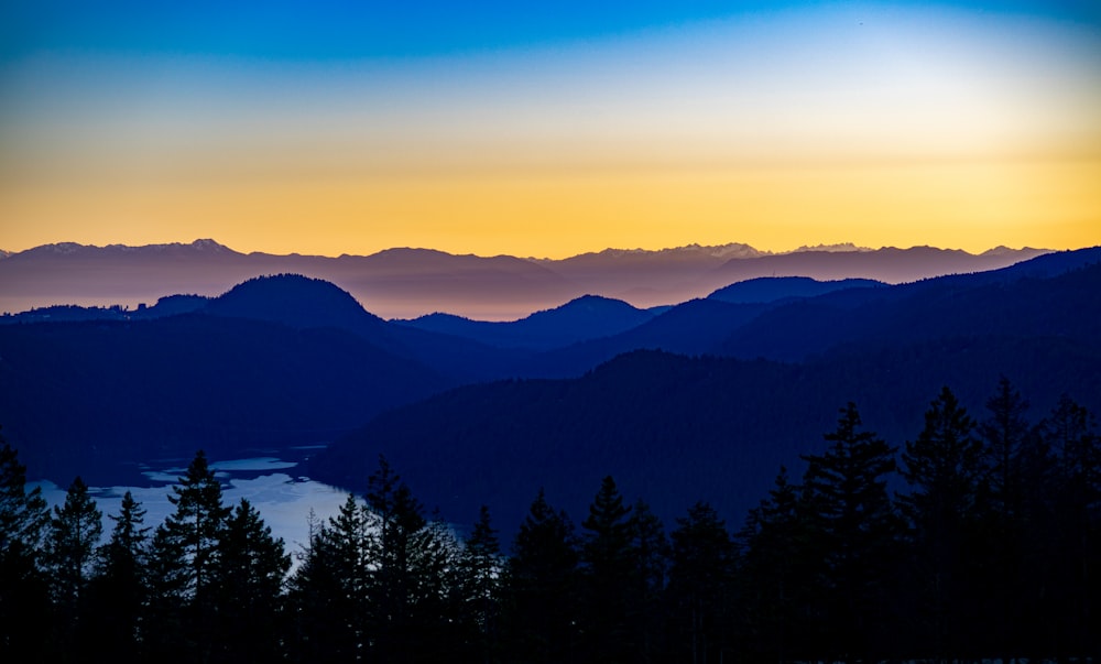 silhouette of trees and mountains during sunset