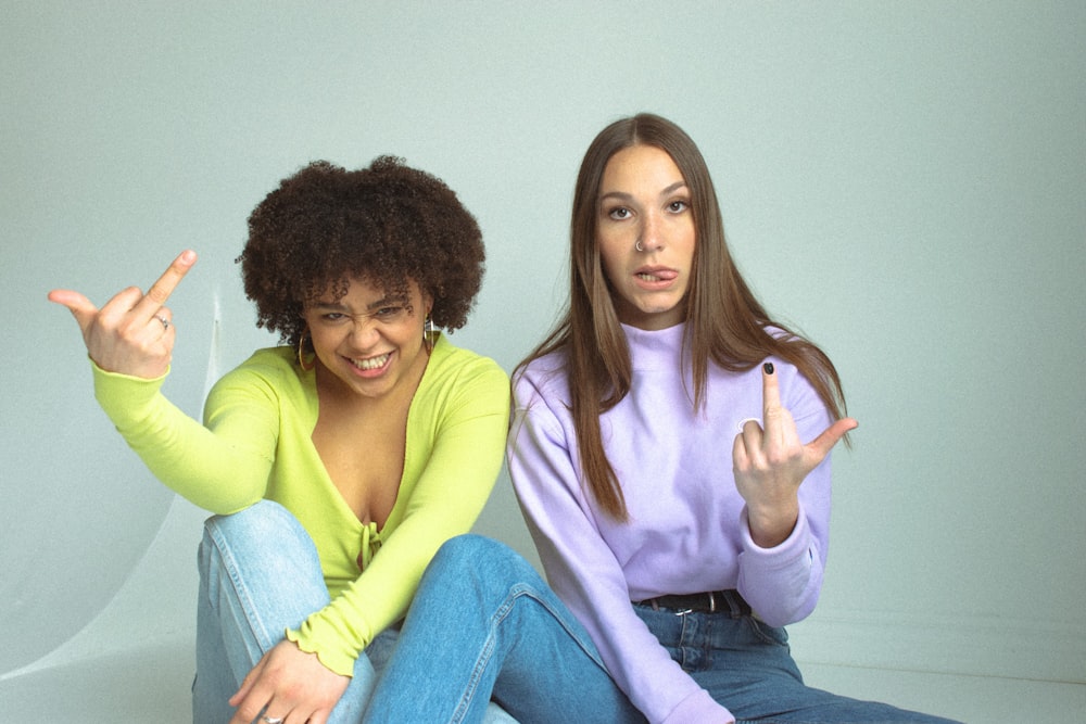 woman in pink long sleeve shirt sitting beside woman in yellow long sleeve shirt