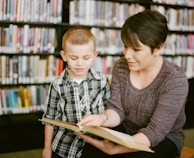 teacher reading beside boy in gray and white plaid dress shirt