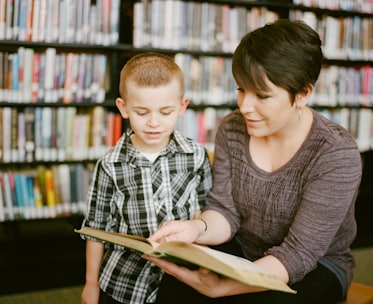 mother helping young kid to read a book