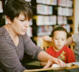 woman in gray long sleeve shirt sitting beside boy in orange crew neck shirt