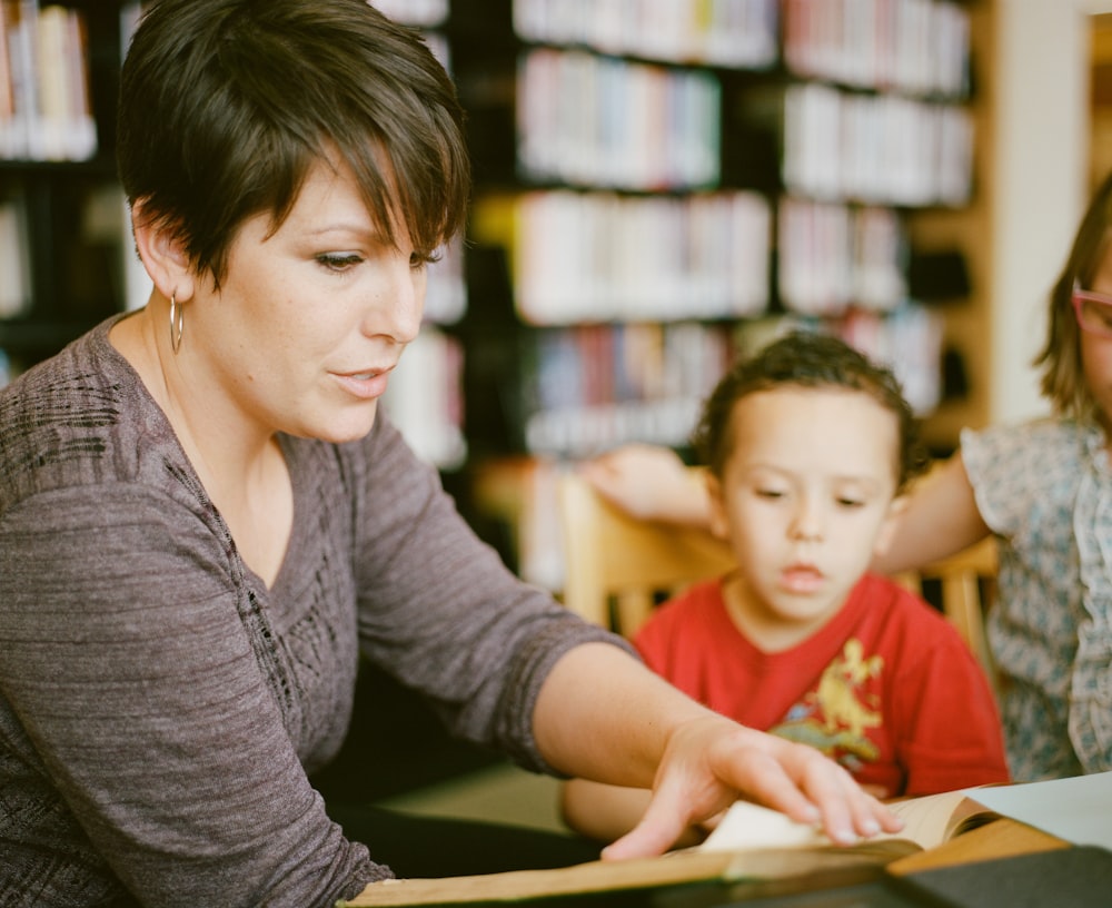 woman in gray long sleeve shirt sitting beside boy in orange crew neck shirt