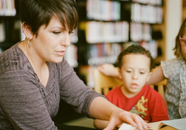 woman in gray long sleeve shirt sitting beside boy in orange crew neck shirt