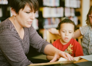 woman in gray long sleeve shirt sitting beside boy in orange crew neck shirt