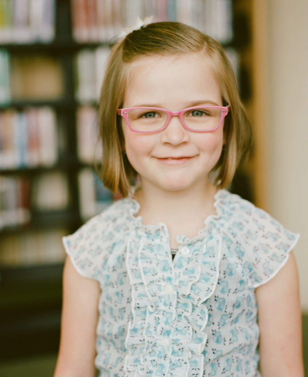 girl in blue and white floral cap sleeve shirt wearing eyeglasses