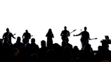 Wide shot of the stage with band silhouettes against a black backdrop.