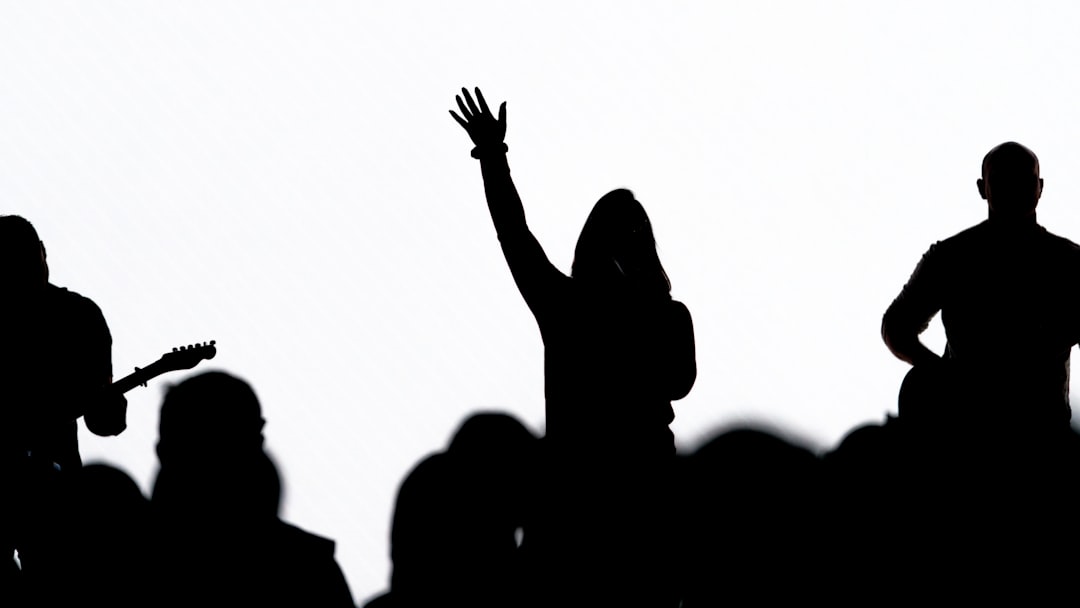 silhouette of people raising their hands, Band performing against a white LED wall