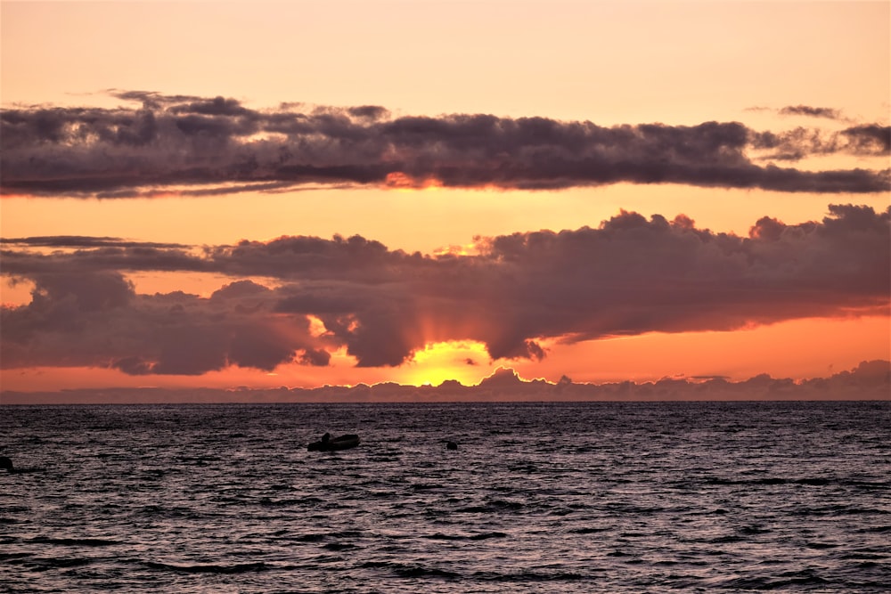 body of water under cloudy sky during sunset