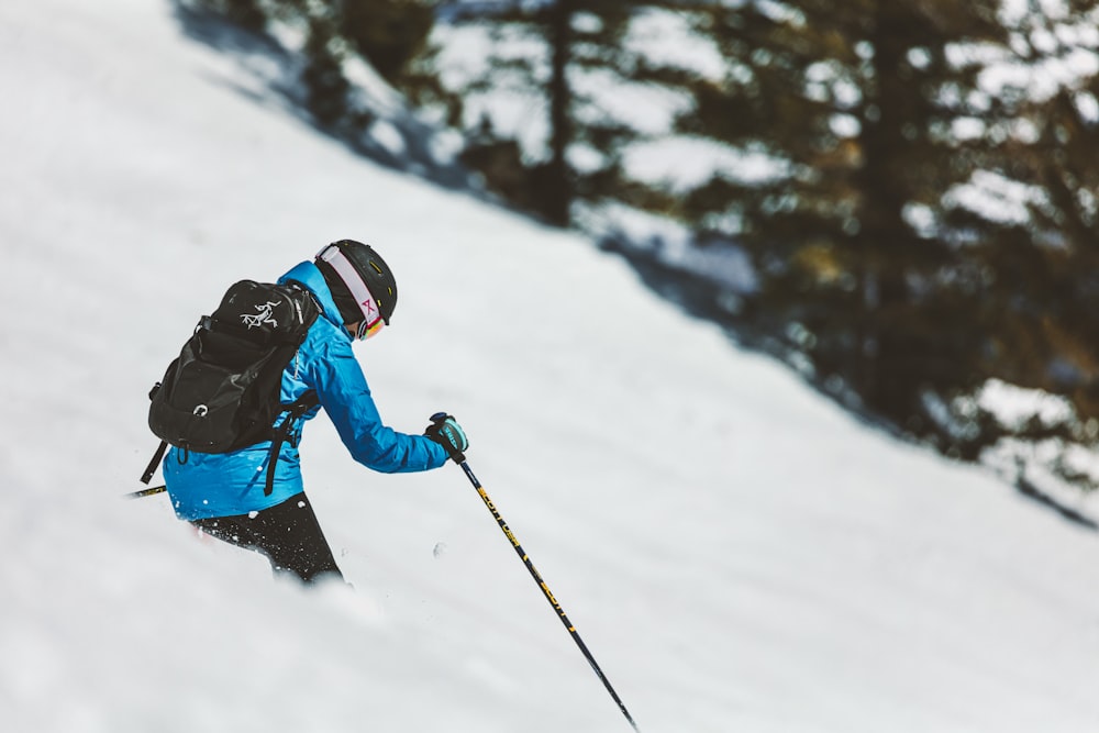 person in blue jacket and black helmet riding ski blades on snow covered ground during daytime