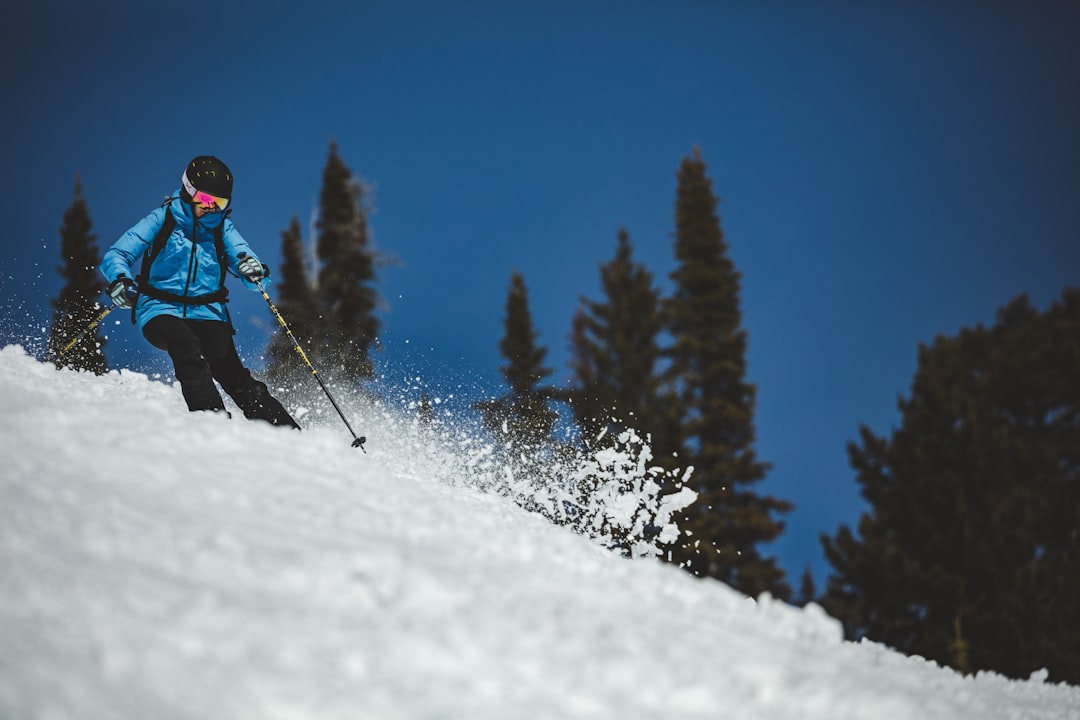 person in red jacket and black pants riding ski blades on snow covered ground during daytime