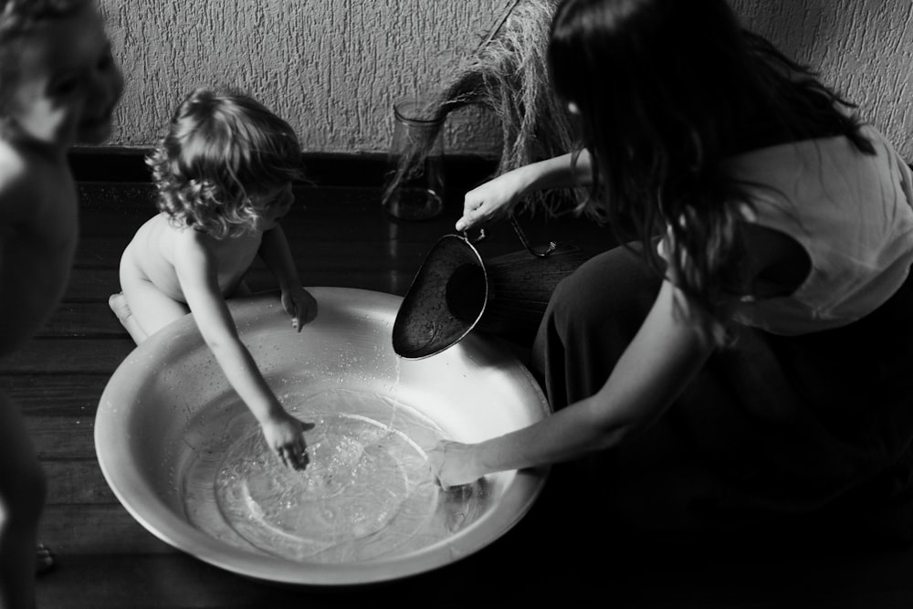 woman in black tank top and black pants sitting on floor with girl in black tank