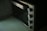 A close-up image of a stainless steel countertop oven with four control knobs is seen. The knobs are aligned vertically, and the oven door has a large handle. The surface appears clean and slightly reflective.