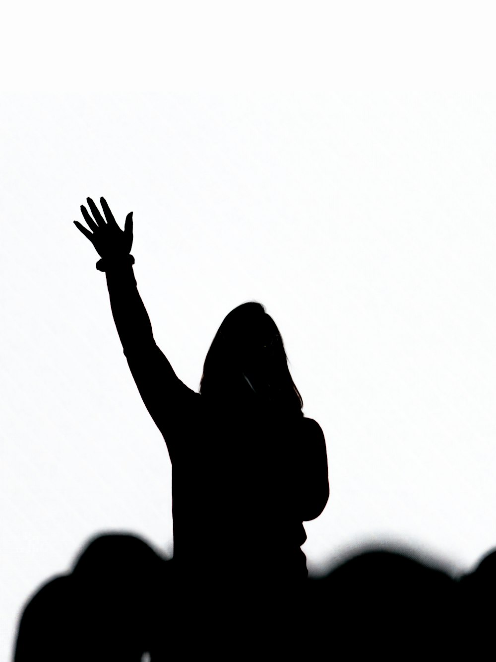 silhouette di persona che alza la mano