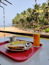 Breakfast tray with fresh fruits and coffee served on a balcony overlooking the ocean.