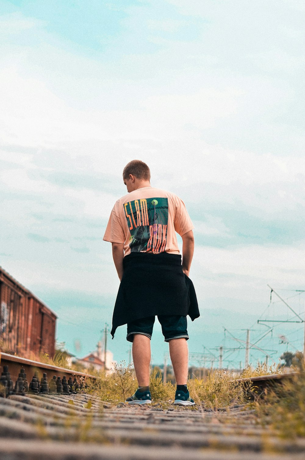 man in white and red crew neck t-shirt and black shorts standing on brown wooden